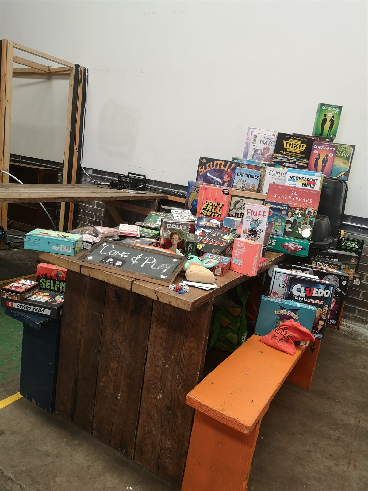 A Dice Pitt table display with board games, dice, and a Come and Play sign.